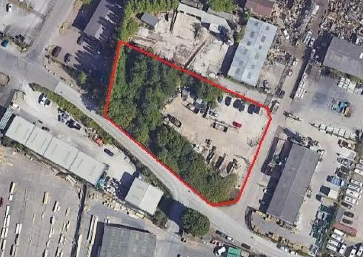 Aerial view of commercial land with red outline, trees, and equipment.