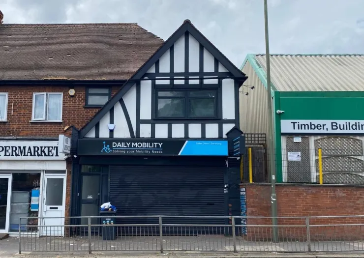 Daily Mobility" storefront with black shutters between a supermarket and timber building.