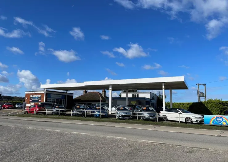 Beauchamp Car Sales forecourt displaying used cars for sale under a petrol station canopy.