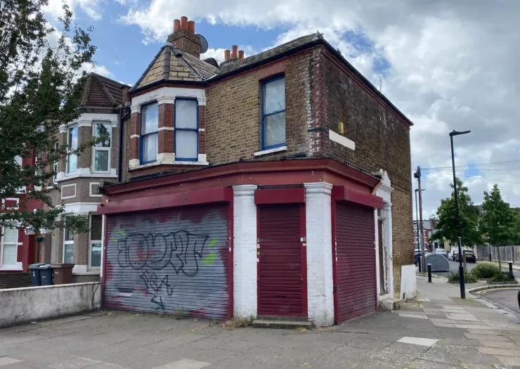 Brick building with red storefront security gates and graffiti.
