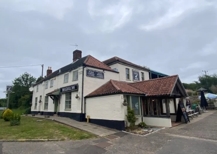 The Gull Inn, a white and tiled roof pub, with signage and accessible ramp.