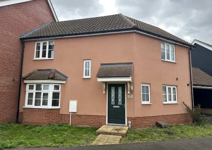 Peach-colored house exterior with green front door, bay window, and tiled roof.
