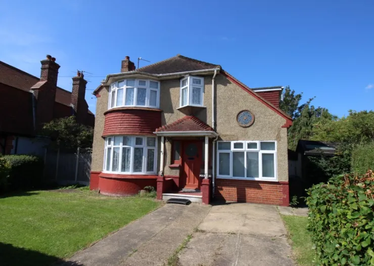 Red and tan detached house with bay windows, front garden, and driveway.