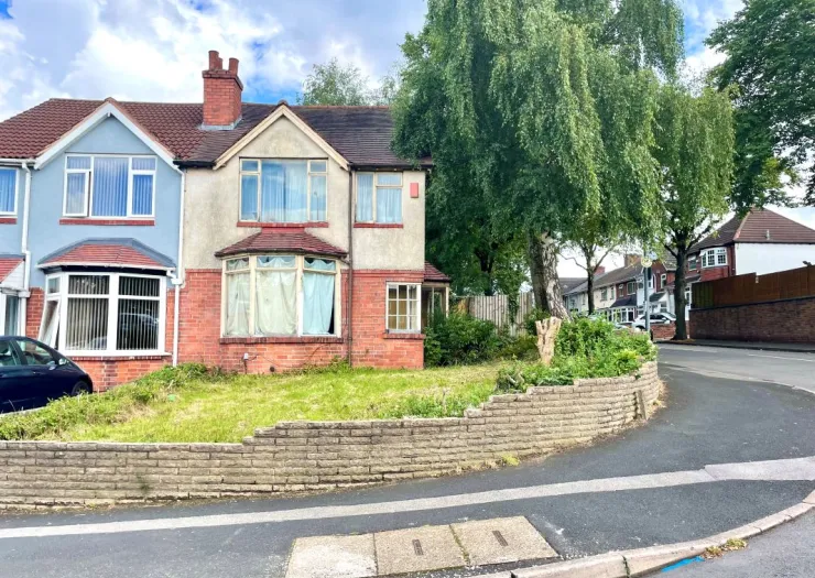 Semi-detached house with front garden and brick retaining wall on a residential street.