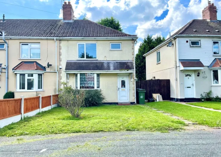 Semi-detached house with cream facade, front garden, and wooden fence under a blue sky.