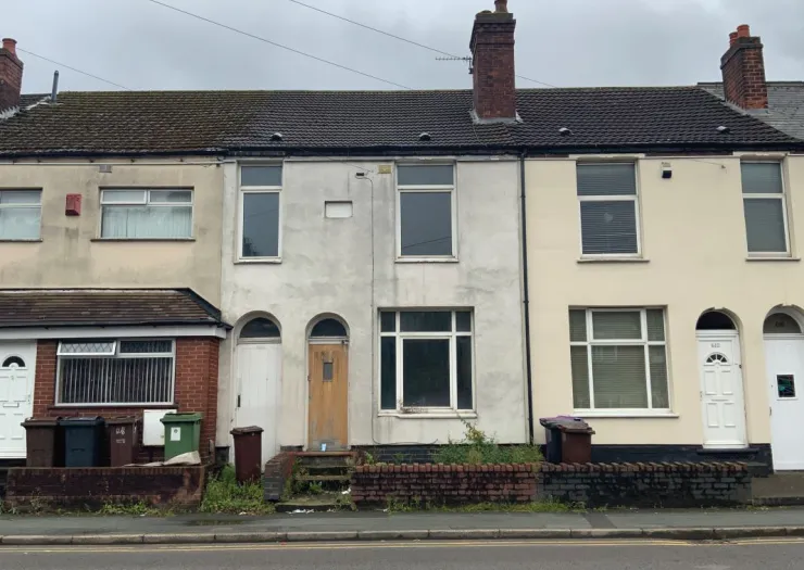 Row of terraced houses, some with weathered exteriors, seen from the street.