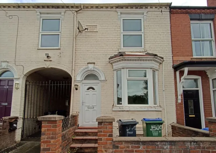 Cream terraced house exterior with bay window and white front door.