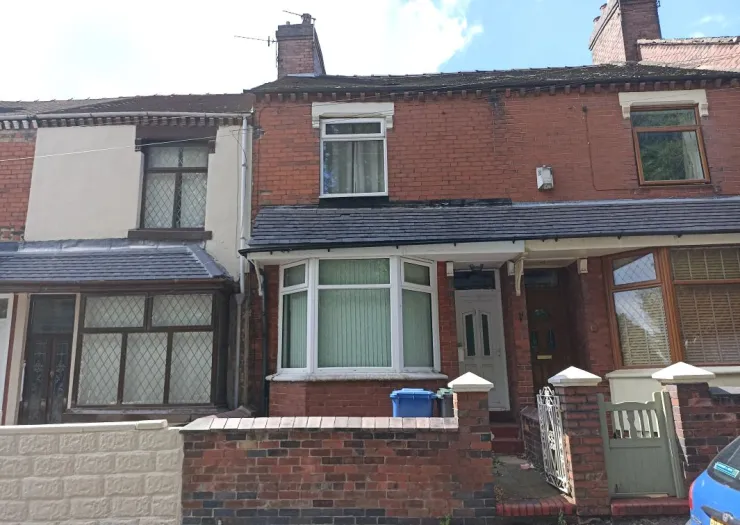 Red brick terraced house with bay window and small front garden.