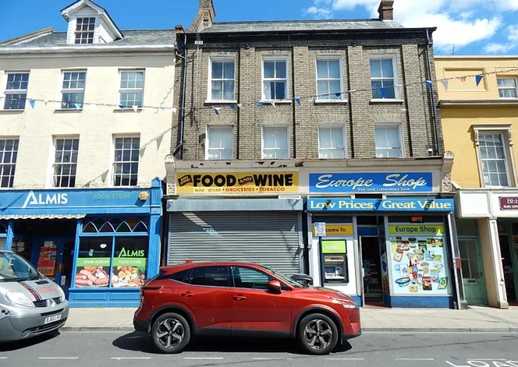 Europe Shop storefront between other businesses on a sunny street. Red car parked outside.