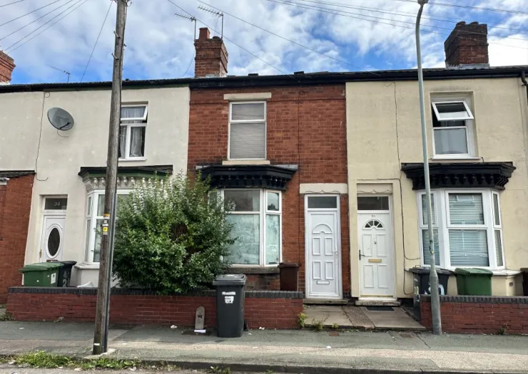 Row of attached brick houses with white doors and bay windows.