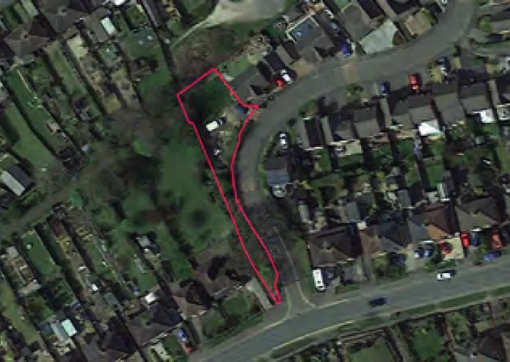 Aerial view of land outlined in red, showing its position within a residential area.