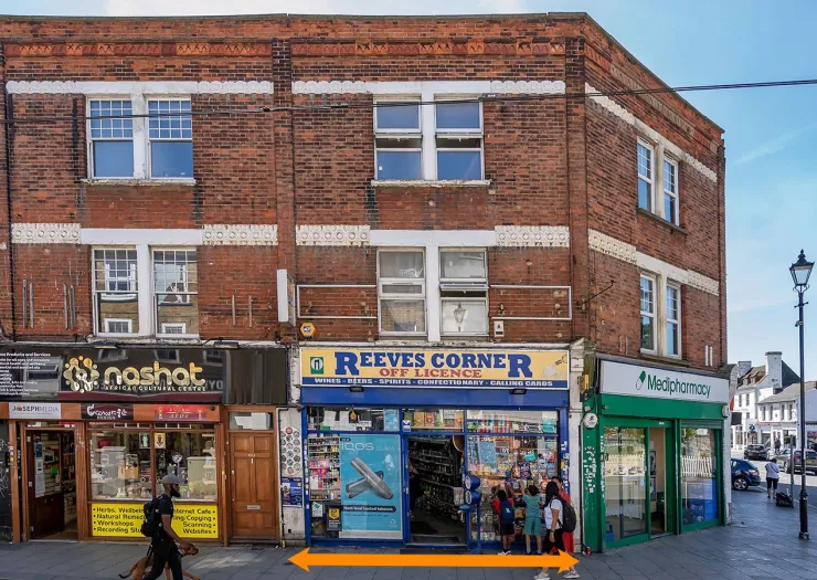 Reeves Corner" off-licence shopfront between other businesses on a UK high street.