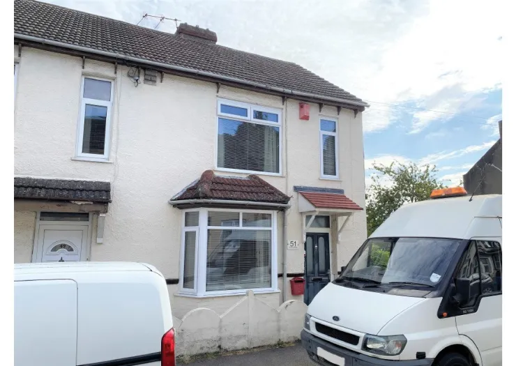 White semi-detached house with bay window and tiled roof. Number 51.