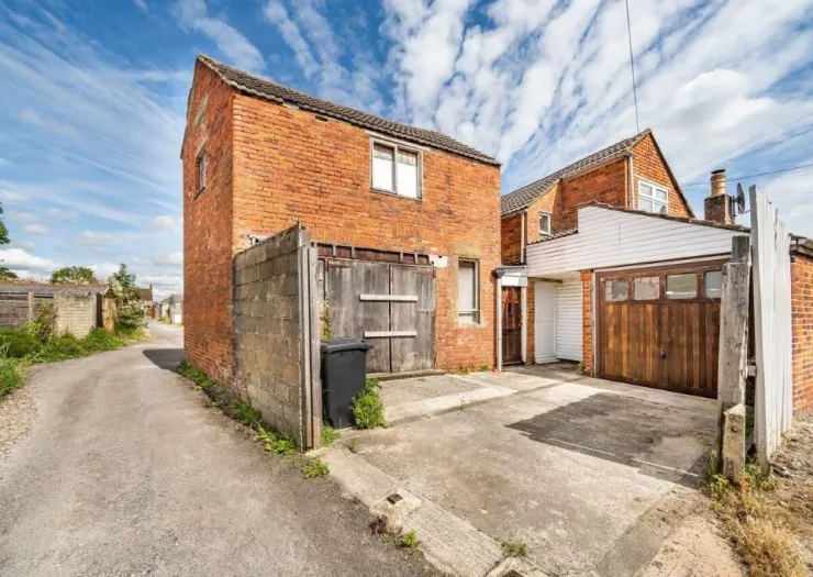 Red brick building with wooden garage doors and driveway access.