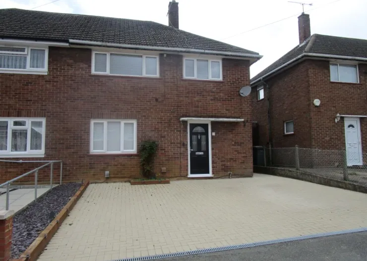 Red brick house with white windows, black front door, and paved driveway.