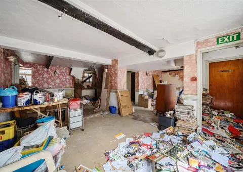 room with beamed ceiling and rubbish on floor