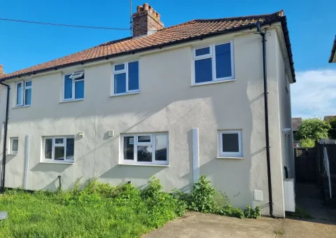 exterior of cream coloured two storey house with green grass front garden