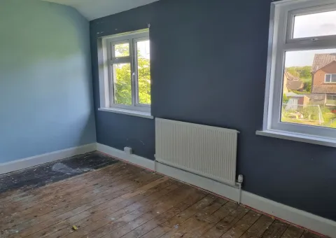 interior of bedroom with slate grey blue coloured walls, wall mounted radiator and exposed floorboards
