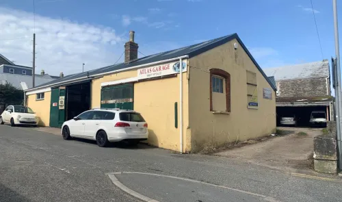 Atlas Garage, a light yellow building with cars parked outside, under a blue sky.