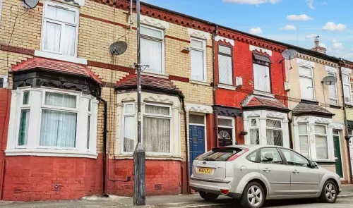 Row of terraced houses in varying colors, with a silver car parked on the street.
