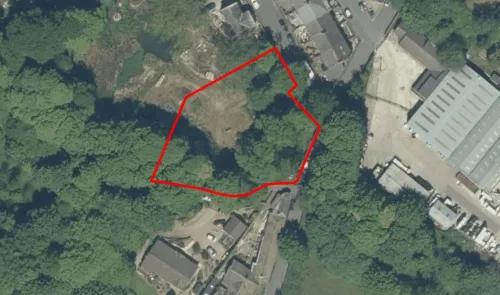 Aerial view of land outlined in red, surrounded by trees and buildings.