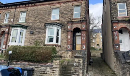 Brick terraced house exterior with decorative porch, bay windows, and stone steps.