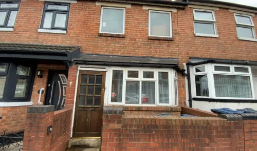 Attached brick house exterior with bay window and wooden front door.