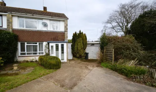 Two-story house with white siding, brown tiled facade, front garden, driveway, and detached garage.