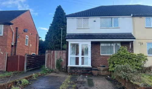 Semi-detached house with white porch and driveway, viewed from street.