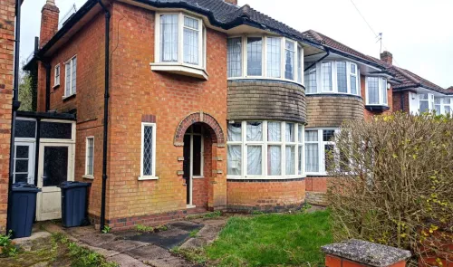Red brick house with curved bay windows and arched doorway.
