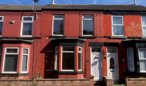 Red terraced house with bay window and white front door.
