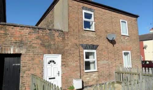 Exterior of a two-story brick house with white door and windows, under a clear blue sky.