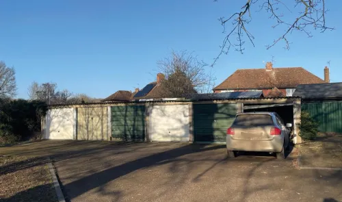 Row of colorful garages with a car backed into one, under a clear blue sky.