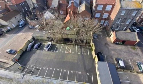 Aerial view of a numbered parking lot, surrounded by buildings and trees.