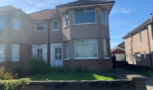 Semi-detached house with bay windows and front garden, seen on a sunny day.