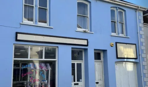 Light blue two-story commercial building with empty storefront signage.