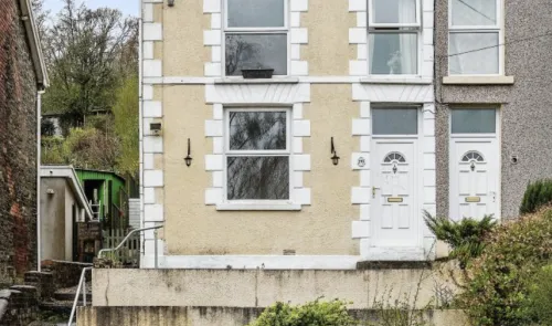 Cream terraced house exterior with white window frames and doors.