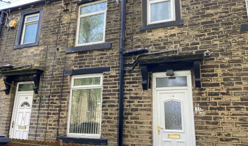 Stone terraced house exterior with white doors, numbered 14 and 16.
