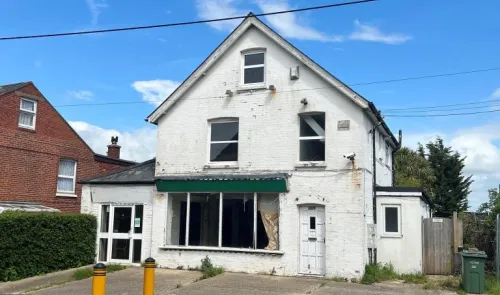 White two-story commercial building with empty storefront and green awning.