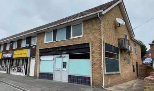 Brick commercial building with frosted windows and a "Premier" convenience store next door.