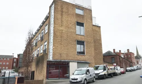 Metropolitan building exterior, tan brick, modern windows, street view.
