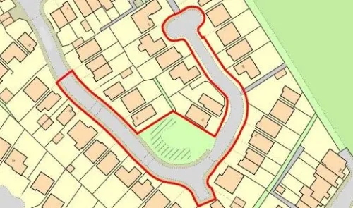 Property site map with highlighted red boundary around houses and green space.
