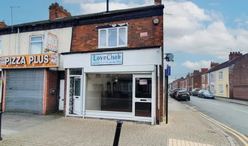 Empty "LoveChak" storefront with "Closed" sign, brick building, street view.