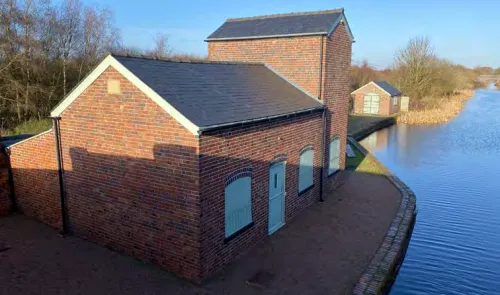 Brick canal-side buildings with slate roofs beside a calm waterway.