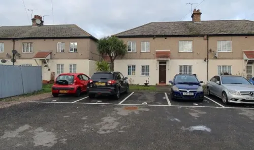 Residential building exterior with parking lot and cars.