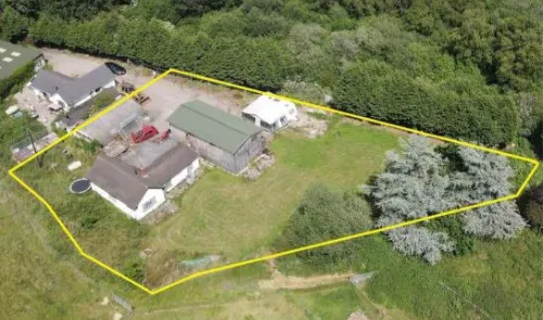 Aerial view of a rural property with house, outbuildings, and land outlined in yellow.