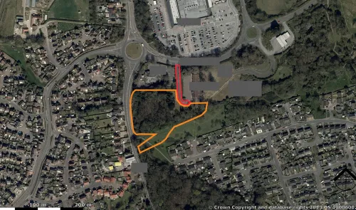 Aerial view of land outlined in orange, near a roundabout and residential area.