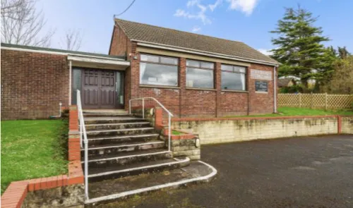 Red brick building with steps and railings leading to a double door entrance.
