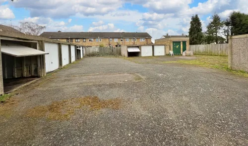 Row of garages with gravel driveway and fenced backyards.