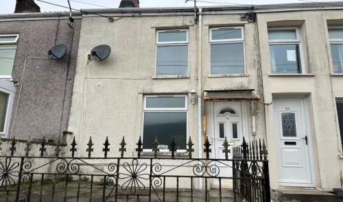 Terraced house exterior with decorative metal fence and white front door.